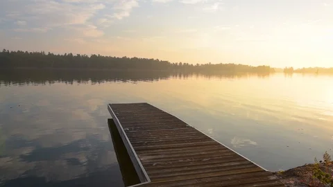 Middle aged man jumping off dock as sun rises in background.  Stock Footage 95026020