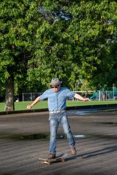 A middle-aged man jumping off of his skateboard because he lost his balance. Stock Photos