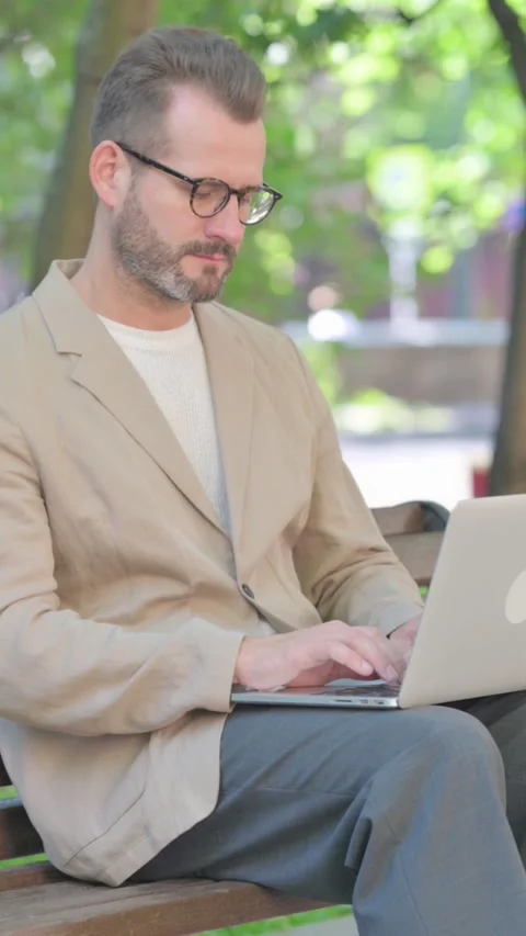 Middle Aged Man with Laptop Looking at Camera while Sitting Outdoor on Bench, Stock Footage 319013987