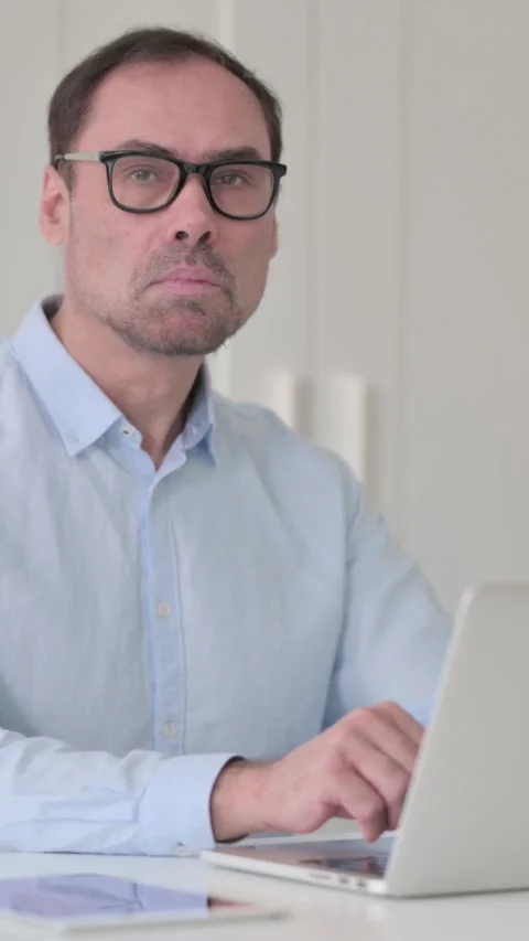 Middle Aged Man with Laptop Looking at the Camera, Vertical Video 스톡 동영상 339584808