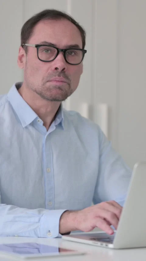 Middle Aged Man with Laptop Pointing at the Camera, Vertical Video 스톡 동영상 339584902