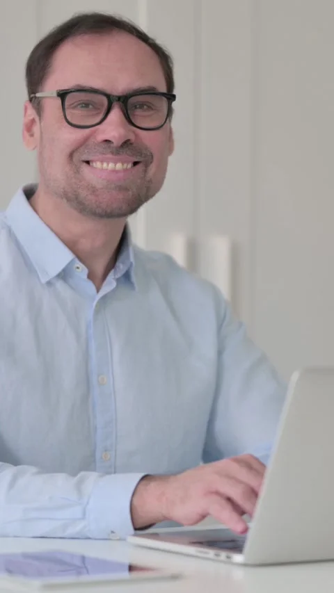 Middle Aged Man with Laptop Smiling at the Camera, Vertical Video 스톡 동영상 339584833