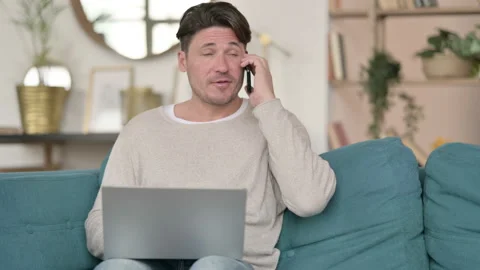 Middle Aged Man with Laptop Talking on Smartphone, at Home Video stock 142379743