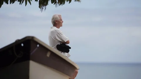 Middle-aged man laughing by a boat on a beach. Vidéo 88370016