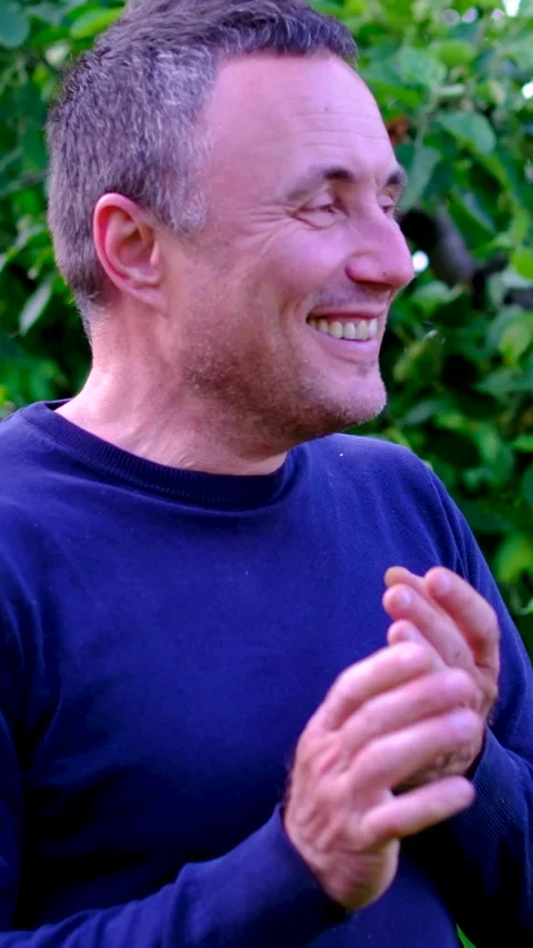 Middle aged man laughing sincerely and clapping hands with joy while enjoying Stock Footage 345744423