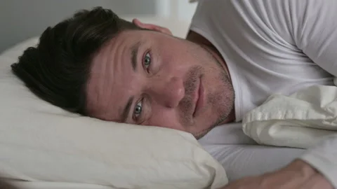 Middle Aged Man Laying in Bed Looking at Camera Video stock 142374580