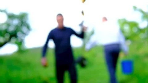Middle aged man leaving garden with lawn mower while elderly father carries Stock Footage 345327660