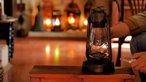 A middle-aged man lights an old kerosene lamp in a cozy room 스톡 동영상 124490817