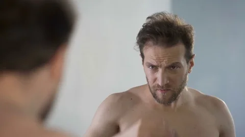 Middle-aged man looking in mirror at his bald patches, hair loss problem Stock Footage 77495938