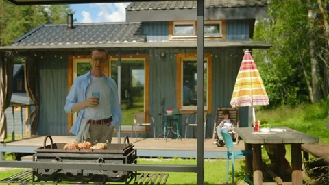 Middle-aged man looks at kebab on grill and drinks beer Stock Footage 339135262