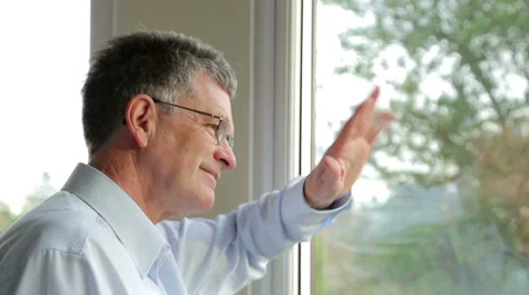 Middle aged man looks out of the window, smiles and waves at someone Stock Footage 33605915