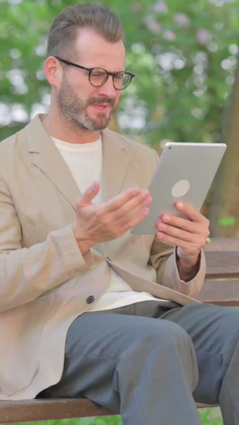 Middle Aged Man with Loss on Tablet while Sitting Outdoor on Bench, Vertical Stock Footage 319012648
