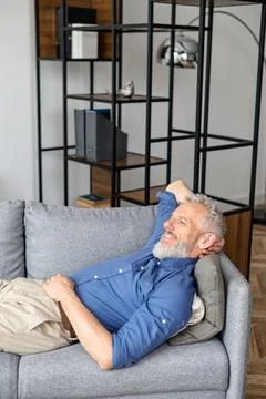 Middle-aged man lying down on the sofa and rests Stock Photos