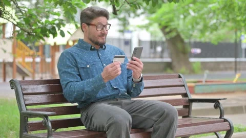 Middle Aged Man Making an Online Purchase with a Credit Card on a Phone 動画素材 311360818