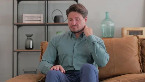 Middle Aged Man with Neck Pain Sitting on Sofa at Home Video stock 287415510