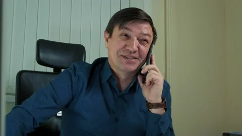 A middle-aged man in the office, talking on the phone and laughing Stock Footage 149075224