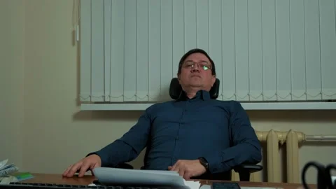 A middle-aged man in an office, thoughtfully turns from in his chair Stock Footage 149075810