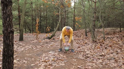 Middle aged man performing kettlebell exercise outdoors in forest Stock Footage 334331730