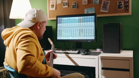 Middle-aged man playing guitar and creating music using equalizer program. Male Stock Footage 160465038