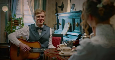 Middle-aged man playing guitar and singing romantic song for lady, 19th century Stock Footage 258512803