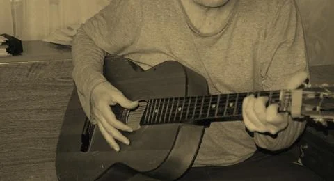 Middle-aged man playing old guitar visible human hands instrument house apa.. 스톡 사진