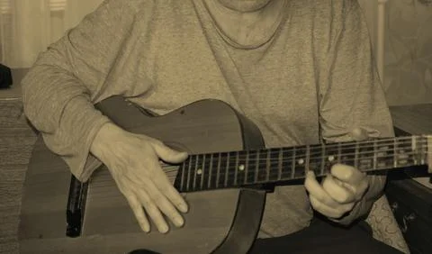 Middle-aged man playing old guitar visible human hands instrument house apa.. Foto stock