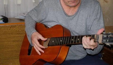 Middle-aged man playing old guitar visible human hands instrument house apa.. Stockfoto's