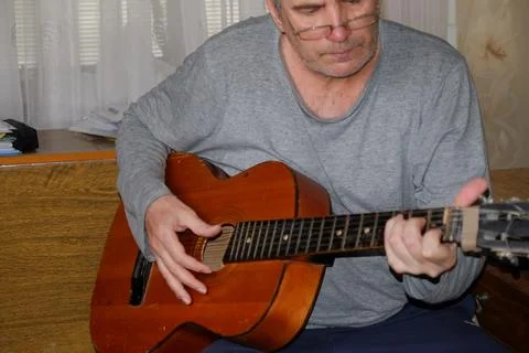 Middle-aged man playing old guitar visible human hands instrument house apa.. Stock Photos