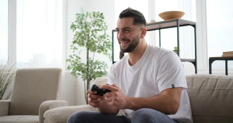 Middle aged man playing the TV game on sofa Stockbeeldmateriaal 150026131