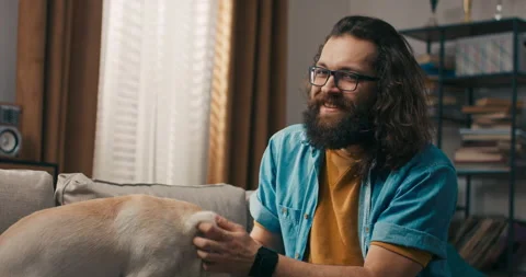 A middle-aged man plays with dog after returning from work. The dog is man's 스톡 동영상 218213311