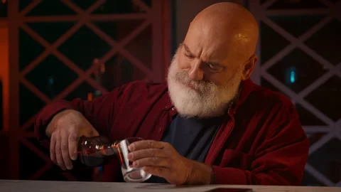 Middle-aged man pours and drinks alcohol alone at home bar, midlife crisis Stock Footage 346714114