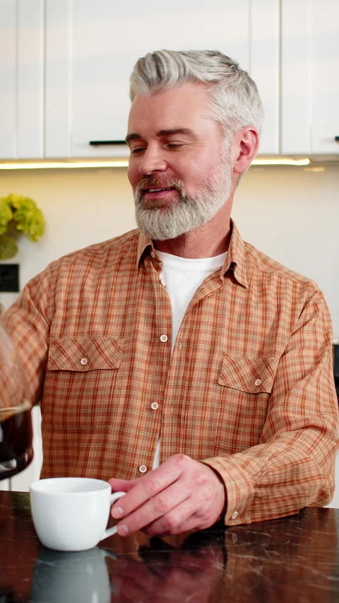 Middle-aged man pours fresh coffee from machine in kitchen enjoying morning Stock Footage 333460006