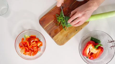 Middle-aged man prepares a fresh salad in a bright kitchen. Stock Footage 302905687