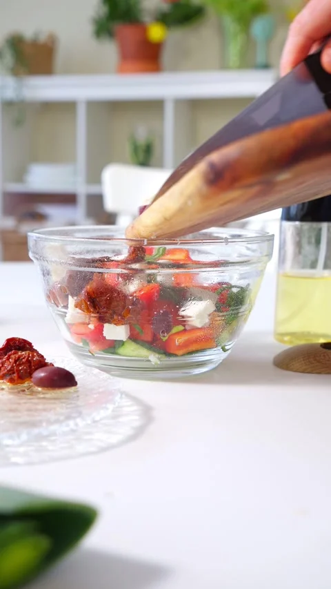 Middle-aged man prepares a fresh Mediterranean salad in a bright kitchen. Stock Footage 302905907