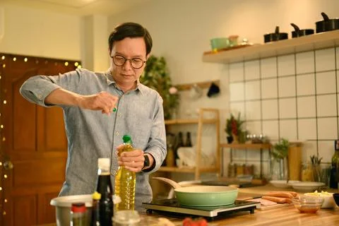 Middle aged man preparing meal on countertop with fresh ingredients Stock Photos