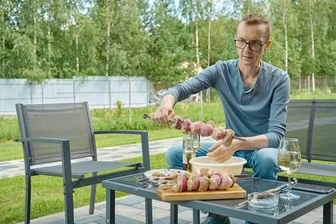 Middle-aged man preparing shashlik on skewer Foto stock