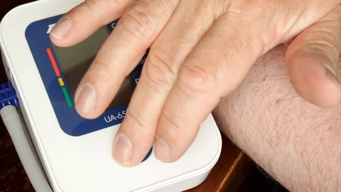 Middle aged man presses start using home blood pressure monitor health check. Stock Footage 96076213