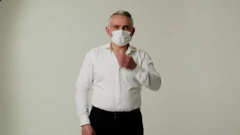 A middle aged man puts on a protective medical mask against coronavirus and Stock Footage 252880420