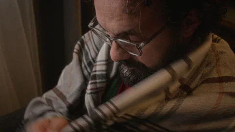 Middle Aged Man Putting on Eyeglasses and Reading Book at Home Stock Footage 341677033