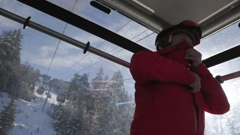 Middle aged man putting on ski jacket, skier, winter clothes, gondola, ski Stock Footage 236192901