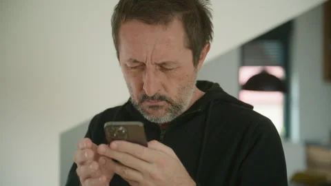 Middle-aged man reacting to bad news on smartphone, covering face in stress.. Stock Footage 336745747