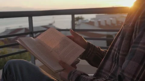 Middle aged man reading book on sunset, freelancer on balcony read during home Stock Footage 143648374