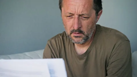 Middle-aged man reading important document looking worried and thoughtful a.. Stock Footage 335826233
