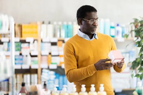 Middle-aged man reading label on box of medicine in drugstore Stock Photos
