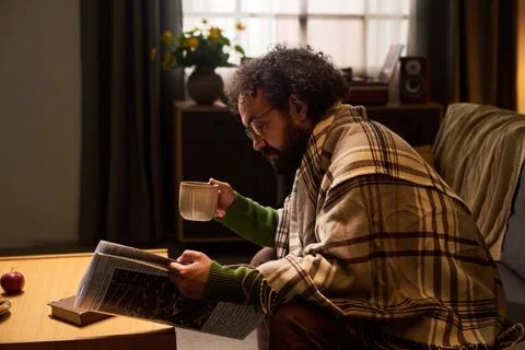Middle Aged Man Reading Newspaper and Drinking Coffee at Home Stock Photos