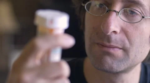 A middle aged man reads the label on a pill bottle - dolly shot Stock Footage 61627517