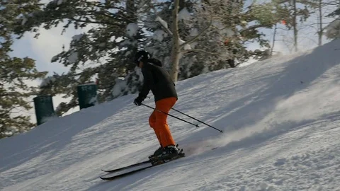 Middle aged man is riding down the ski slope turning and speeding Stock Footage 112019799