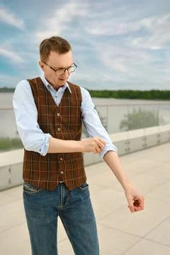 Middle-aged man rolling up sleeves near river on sunny day during afternoon.. Stock Photos