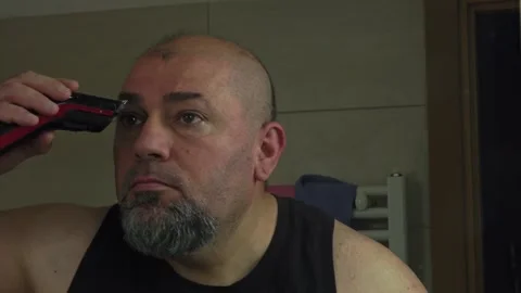 Middle-Aged Man Safely Trimming His Eyebrows with Clipper Stock Footage 337164634