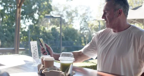 Middle-aged man scanning QR code with phone at outdoor counter, taking tray, Stock-Footage 342085130